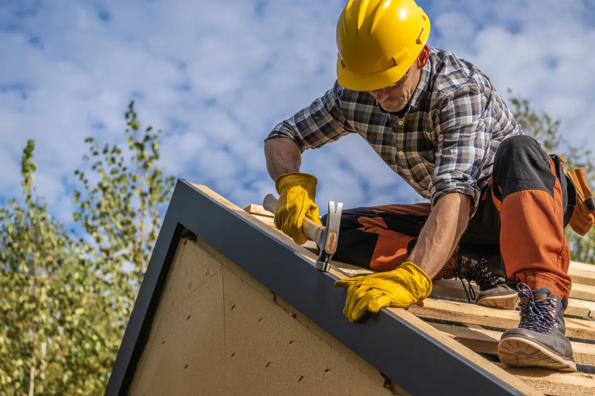 Roofer hammering on house roof construction.