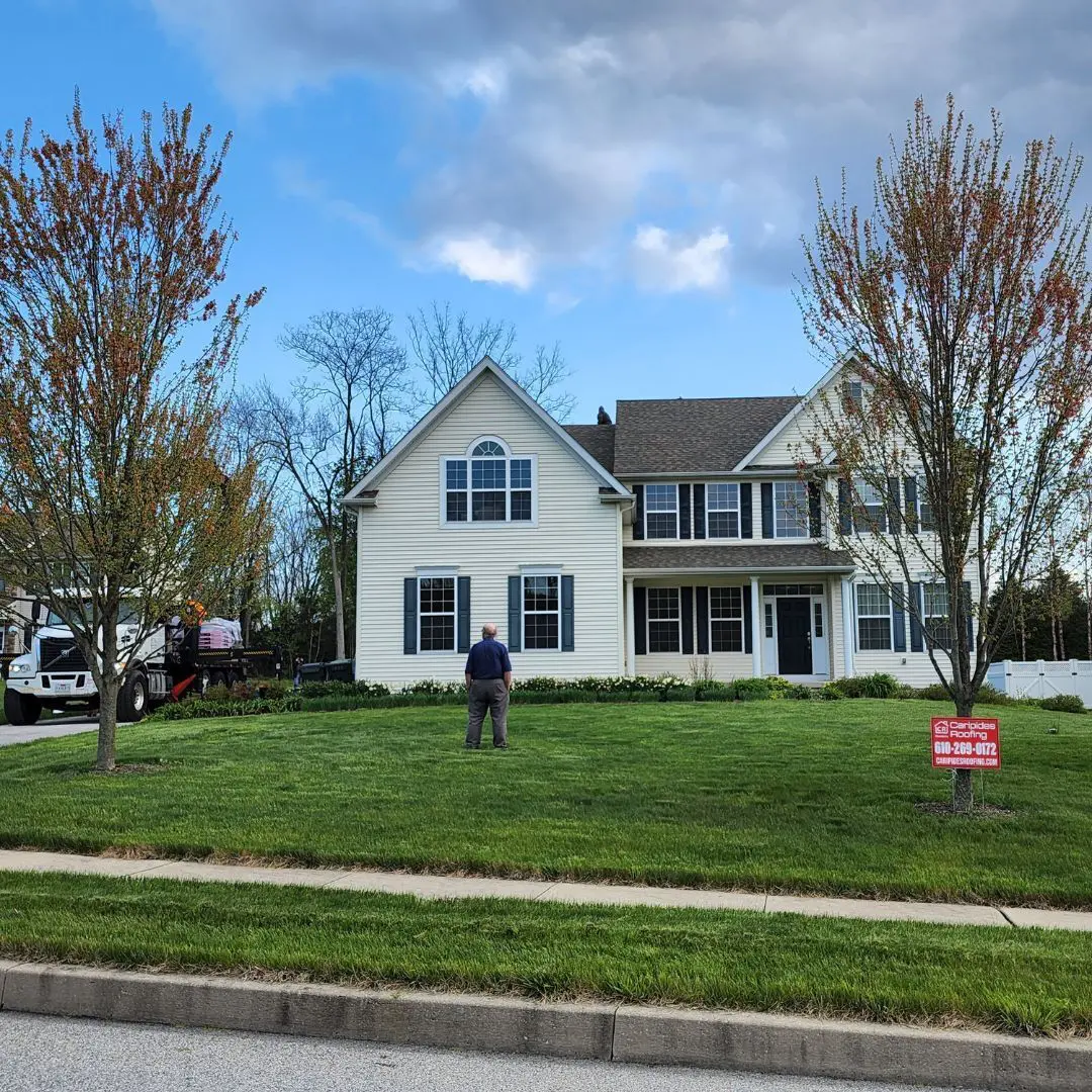 Person standing outside a large suburban house.