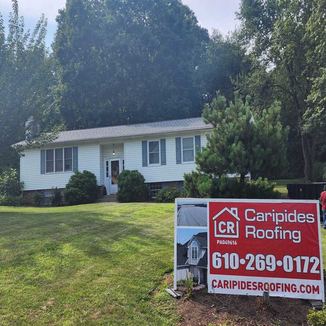 House with Caripides Roofing sign in yard.