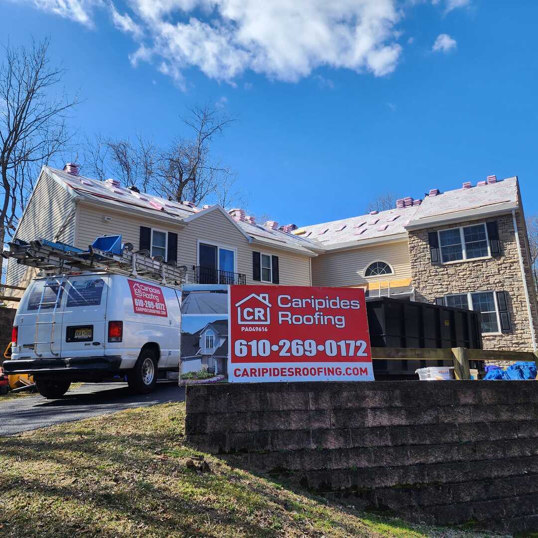 House with Caripides Roofing sign and van.